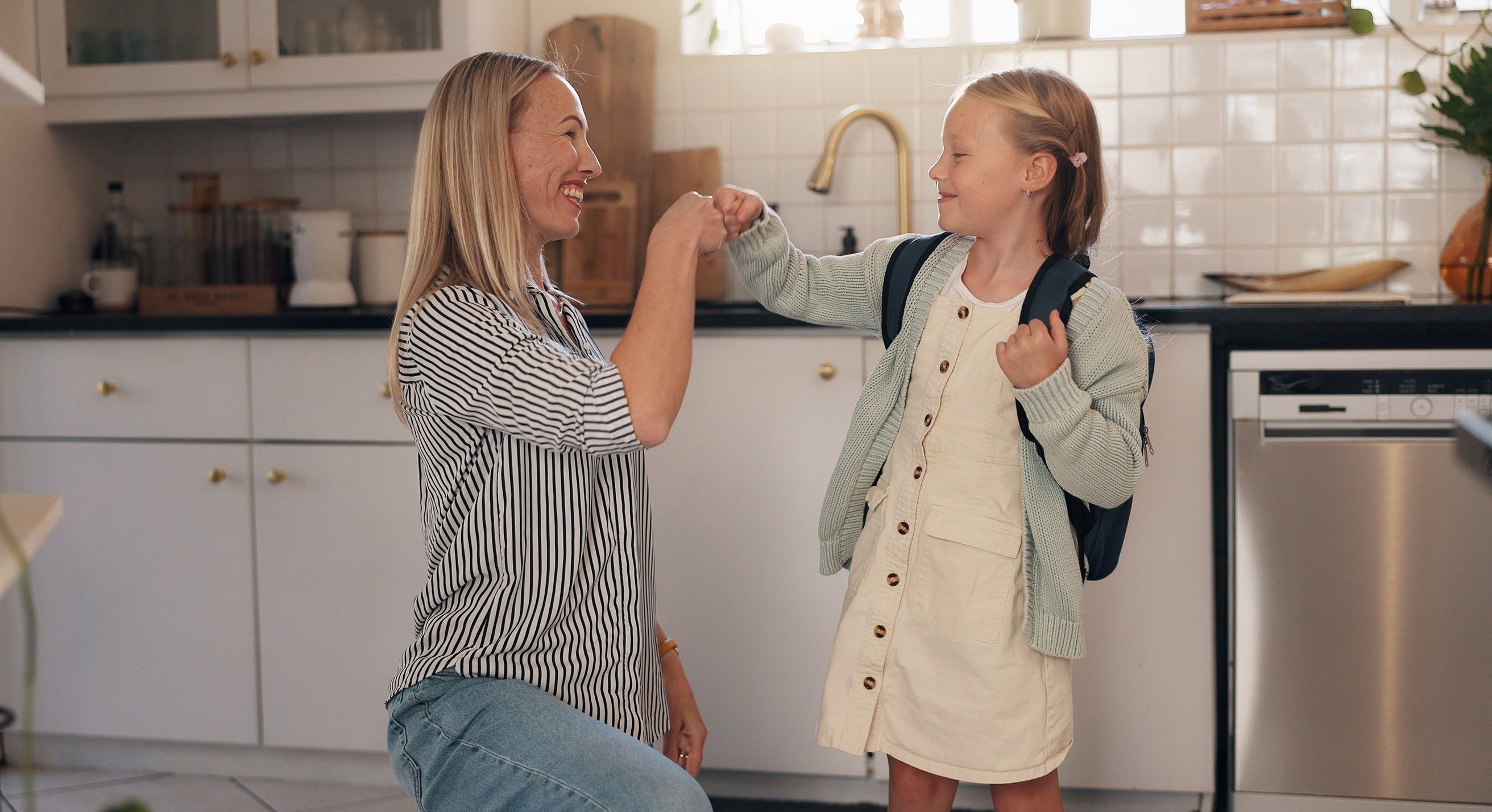 A mom and her daughter fist-bumping in the kitchen