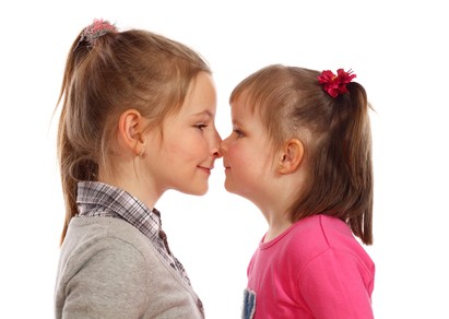 Two young sisters posing together in a studio