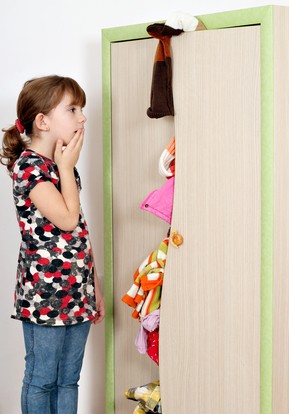 shocked little girl looking into a messy closet